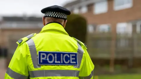 Getty Images A stock image of a police officer in a high-viz police jacket. The officer's back is to the camera.