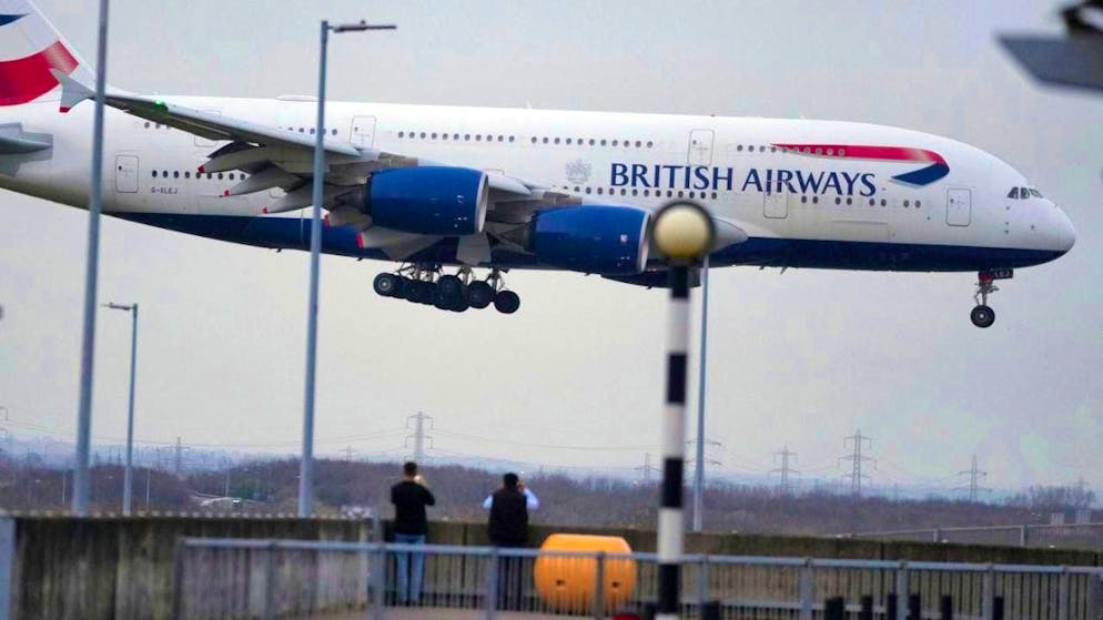 ARCHIVE - People watch as a British Airways plane lands in London. Photo: Kin Cheung/AP/dpa/Archive image