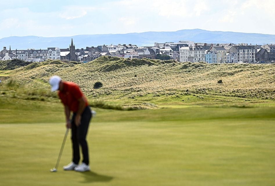 Rory McIlroy on the 16th green with Portrush in the background