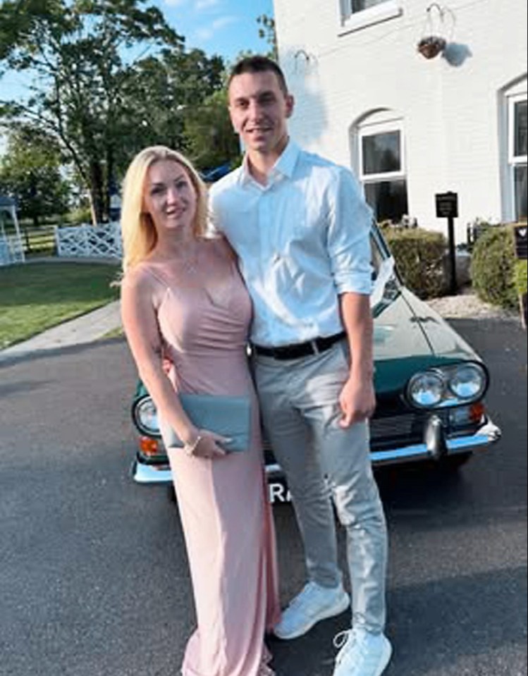 Couple posing in front of a vintage car.