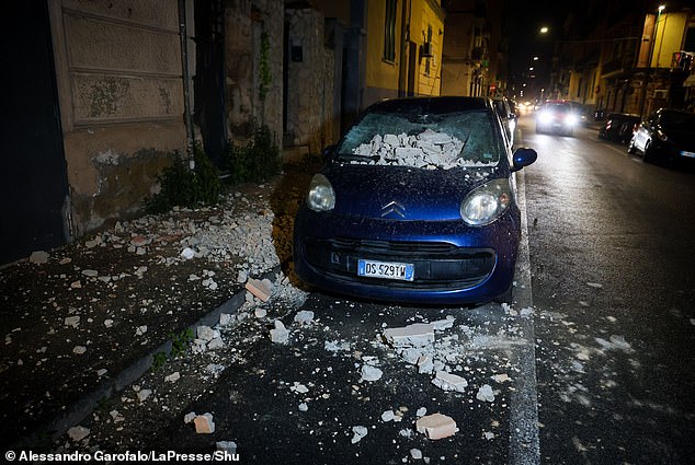 Rubble falls from buildings, crushing a vehicle below, after the powerful quake hit the Naples area early this morning