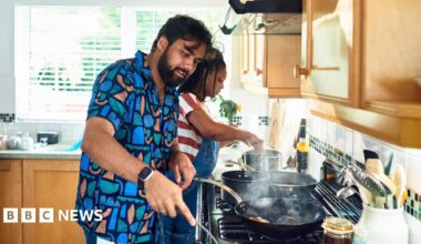 Couple cook on a hob in a kitchen.