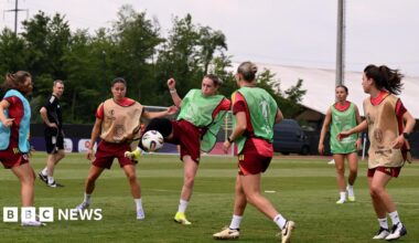 Wales women celebrate win, in their muddied kit with hands in the air
