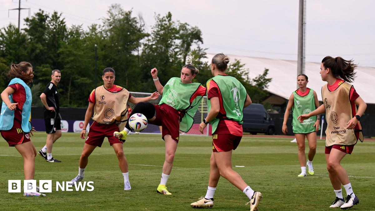 Wales women celebrate win, in their muddied kit with hands in the air
