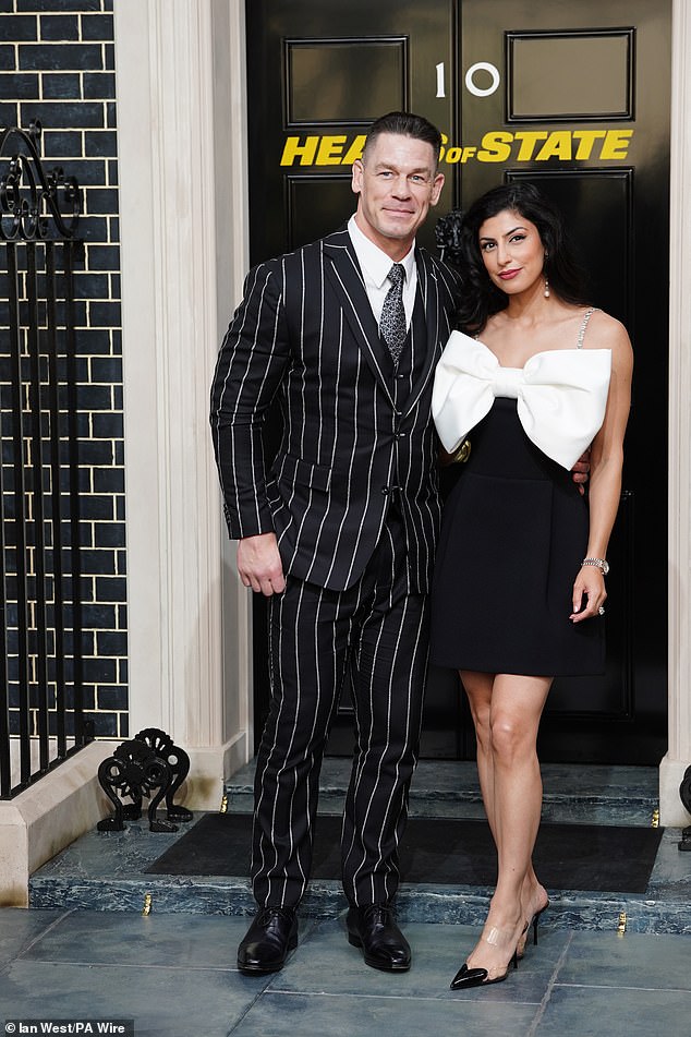 The professional wrestler cut a dapper figure in a black and white pinstriped suit which he teamed with a smart white shirt and a matching tie