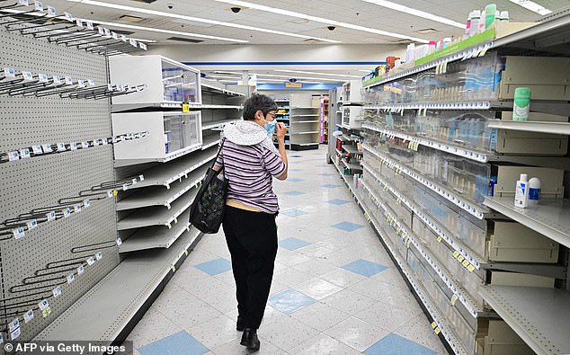 A woman browses through near empty shelves at a Rite Aid store in Alhambra, California, in 2023