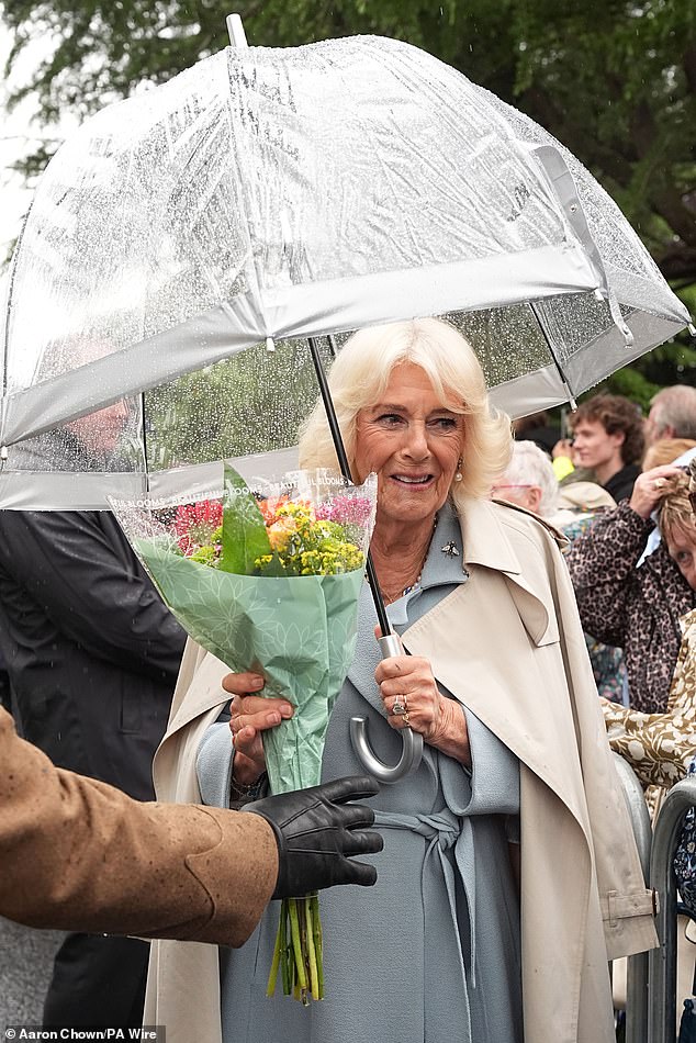 Camilla put on a chic display in a longline blue coat with a brown mac over the top to protect her from the showers