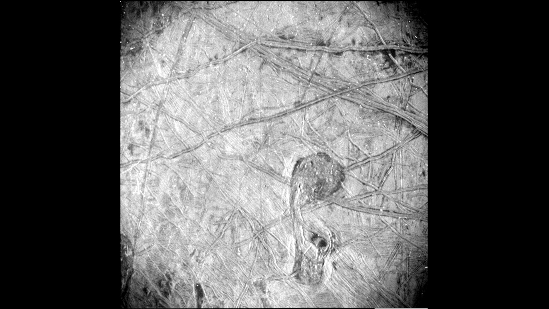A black and white photo of the criss-crossed sections of ice on the surface of Europa.