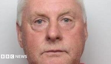 A close crop of a mugshot of Paul Richardson. He is in his sixties and has a pink face, white hair, and watery blue eyes.