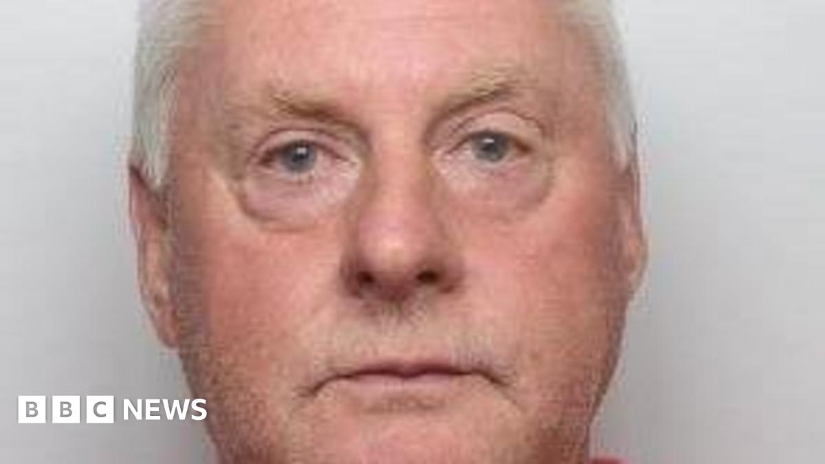 A close crop of a mugshot of Paul Richardson. He is in his sixties and has a pink face, white hair, and watery blue eyes.