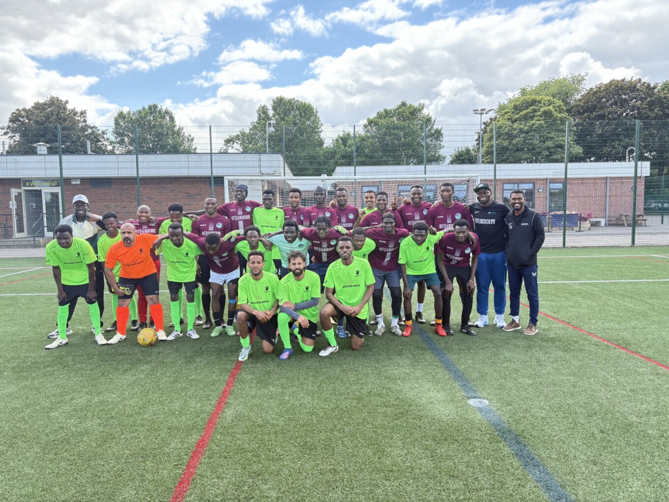 A group of footballers of all ages pose for a team photo. Some are wearing purple, others are wearing fluorescent yellow.