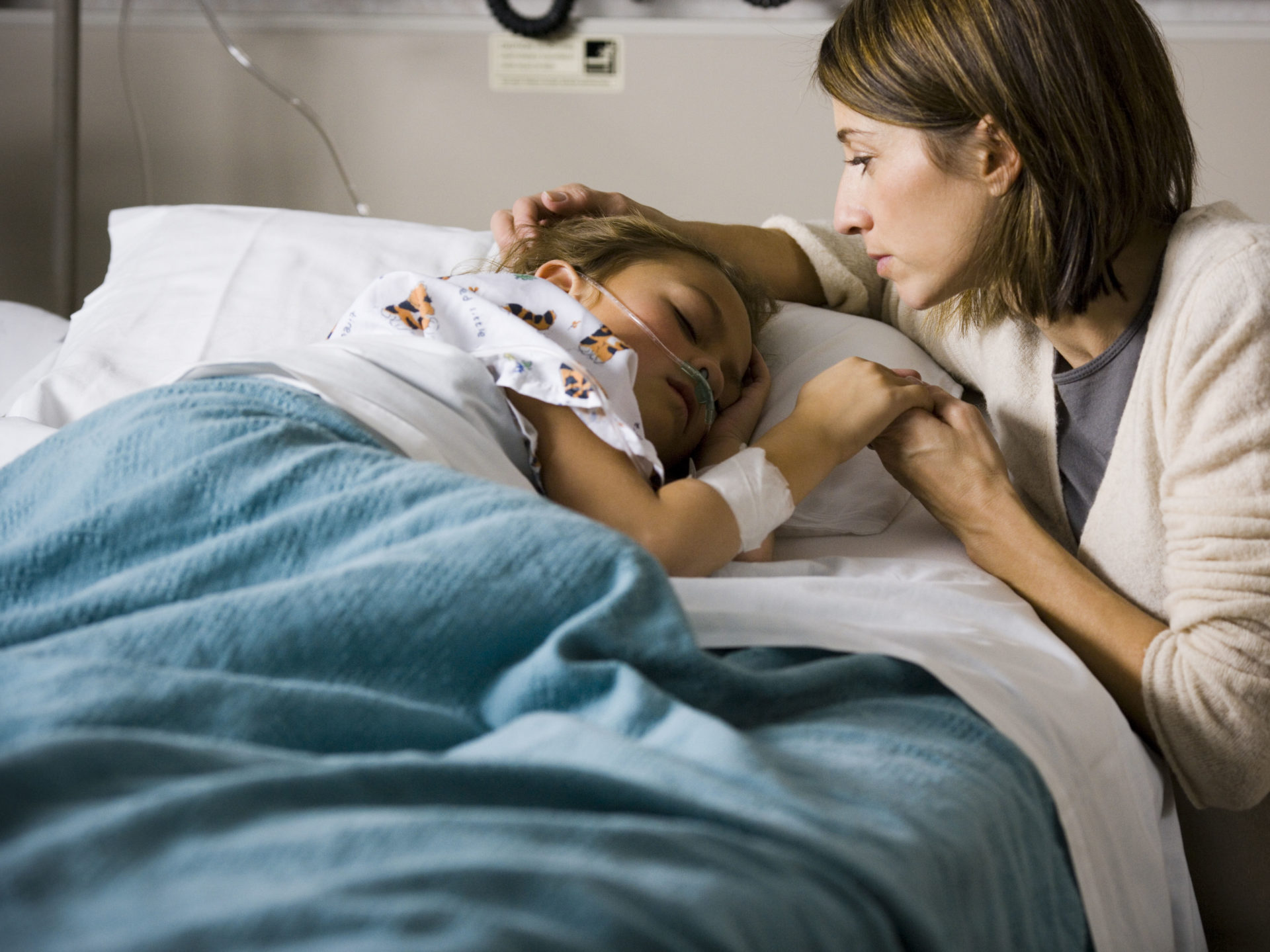 Woman holding hands with young girl in hospital. 
