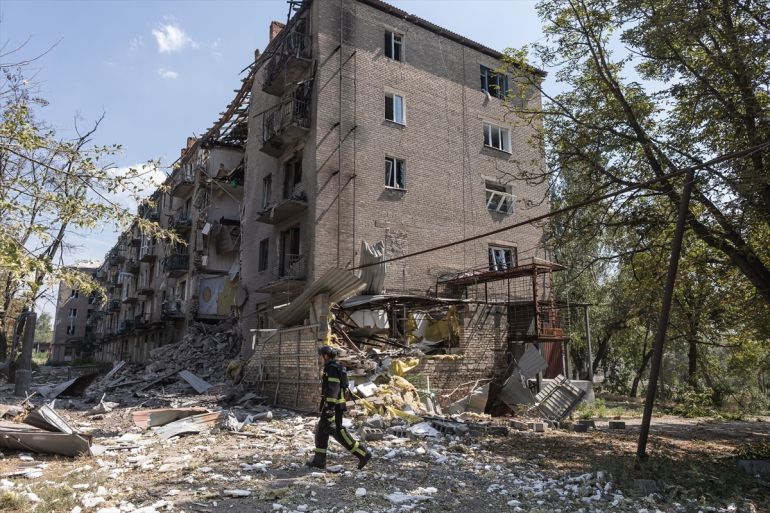 a firefighter walks near a damaged building