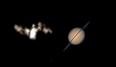 A blurry, bright object resembling the Bat-Signal appears on the left, while the planet Saturn with visible rings is clearly seen on the right, both set against a black background.