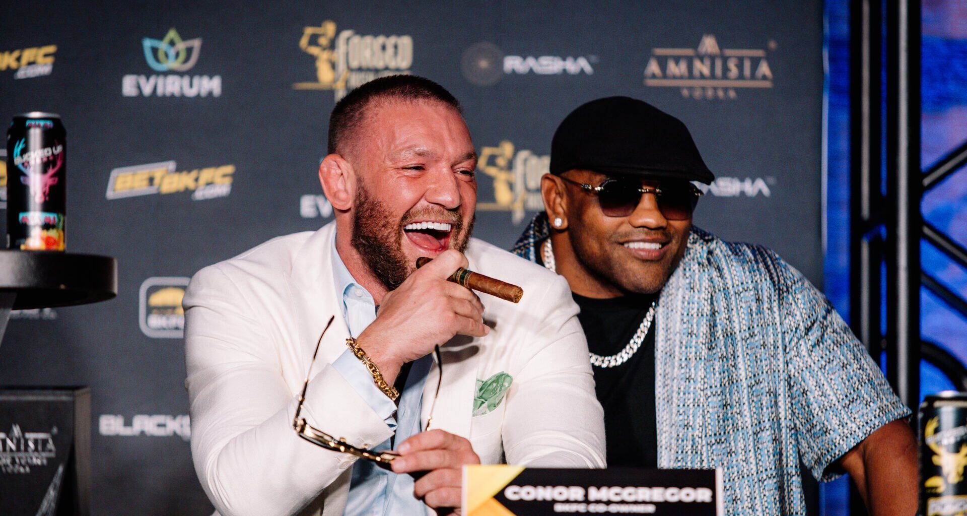 Conor McGregor holding a cigar alongside Yoel Romero