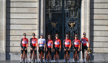 Team shot of the Ineos 2025 Tour de France building, the riders standing outside of a large building