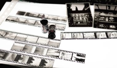 Black and white photo negatives, film canisters, and two printed photographs are displayed on a lightbox, showcasing various urban and landscape scenes.