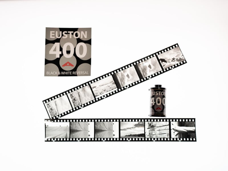 A roll of Euston 400 black and white reversal film, its box, and two strips of developed black and white negatives displayed on a white background.