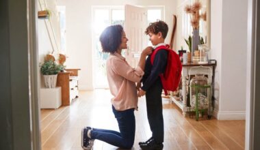 Mother At Home Getting Son Wearing Uniform Ready For First Day Of School
