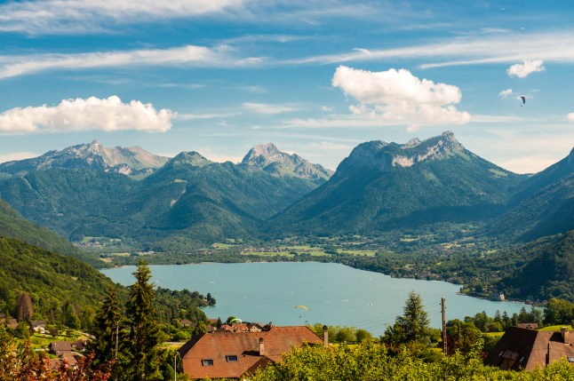 A view of Lake Annecy, in France, with Paragliders above it