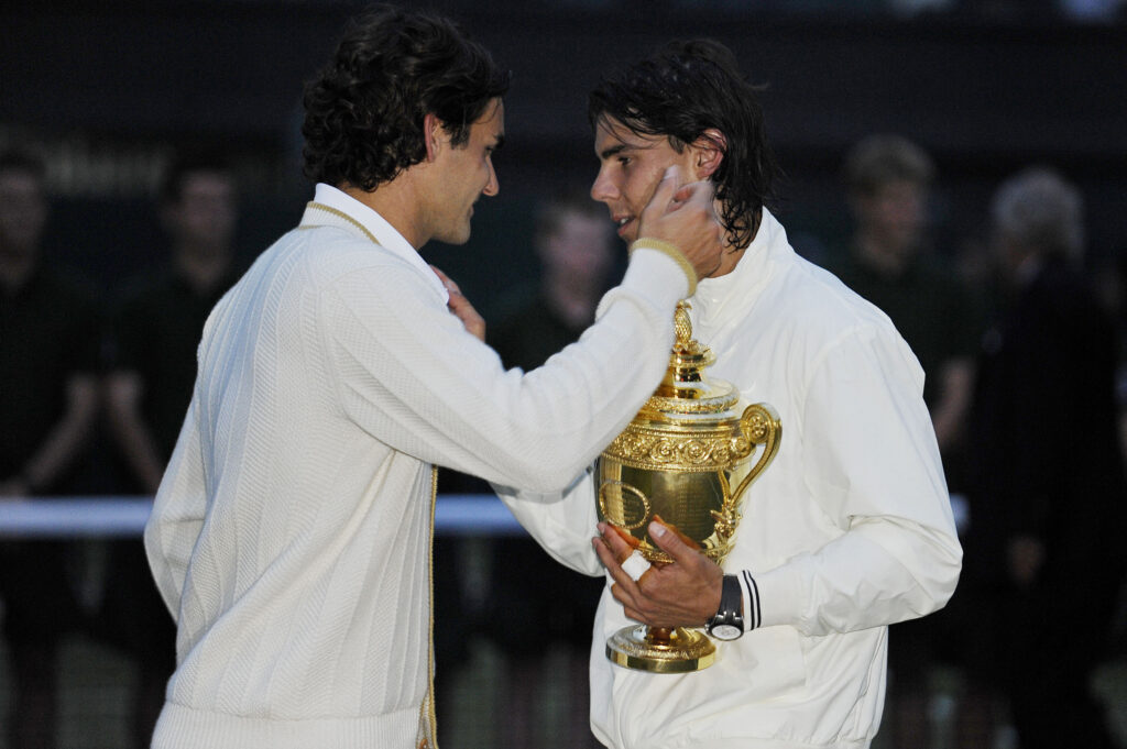 Roger Federer embraces Rafael Nadal, who holds the Wimbledon trophy