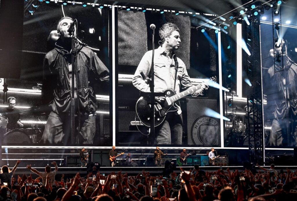 Noel Gallagher and Liam Gallagher on the big screen as Oasis play gig on their comeback tour