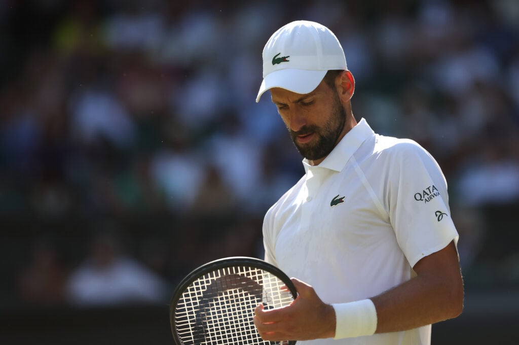 Novak Djokovic looks at his racket during his Gentlemen's Singles Semi-Final match against Jannik Sinner at The Championships - Wimbledon 2025