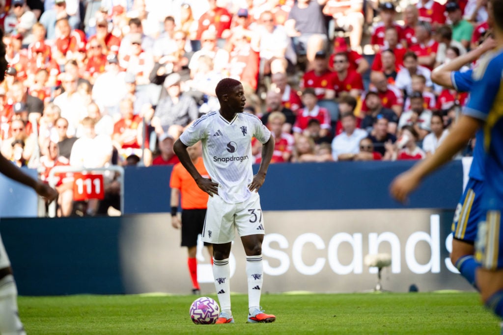 Kobbie Mainoo with hands on his hips for Manchester United in white away kit.