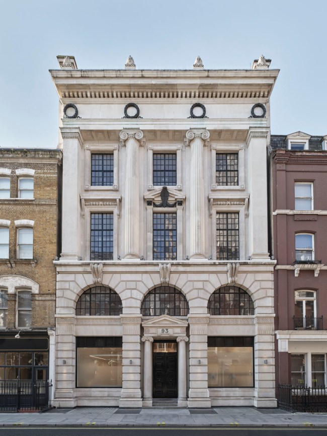 This photo shows a grand, white classical-style building with columns, decorative arches, and large windows. The building