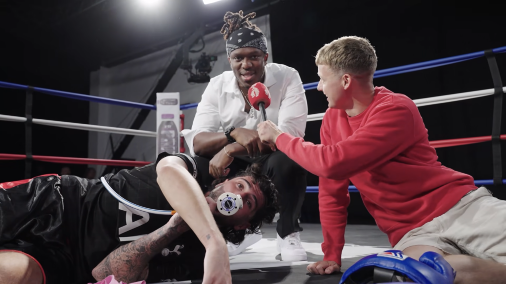KSI gives an interview to Fred Beck as he kneels over Danny Aarons, who has suffered a severe injury