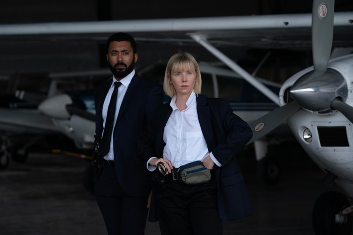 Phil Parhatka and Karen Pirie in Karen Pirie wearing black and white suits, standing in front of small aeroplanes and looking ahead.