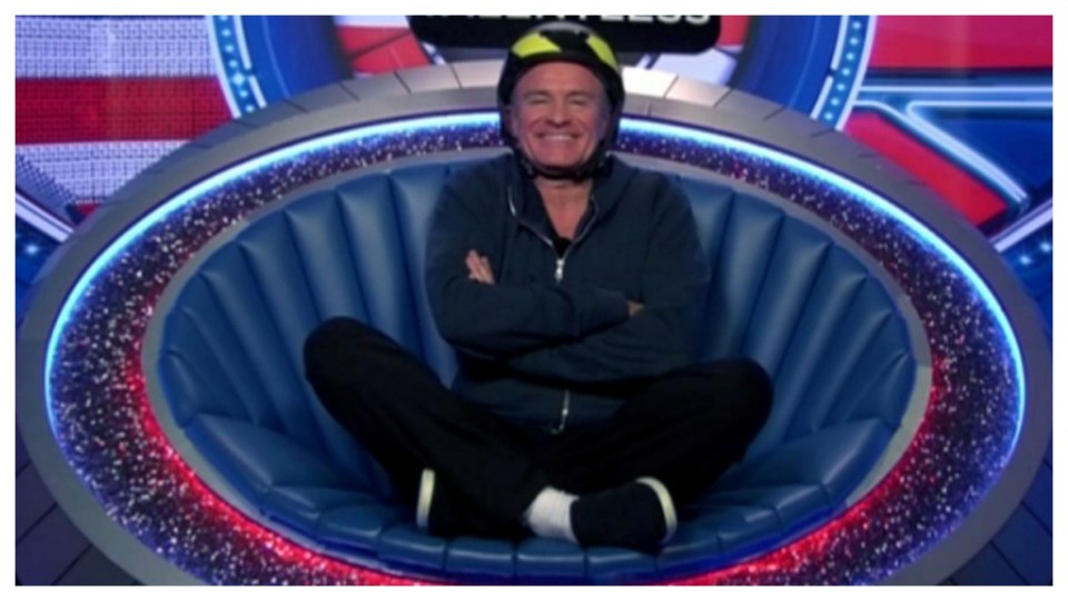 Man in helmet sitting in a futuristic chair.