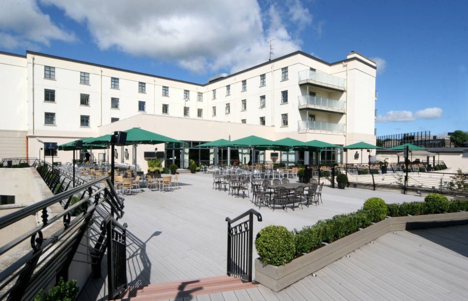 Outdoor patio area with tables and chairs, next to a large building.