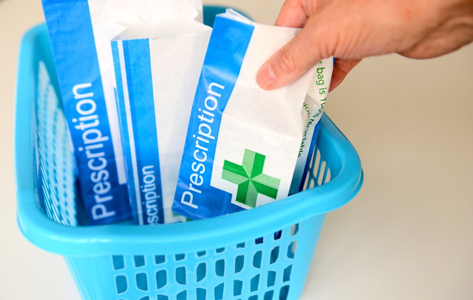 Hand placing prescription bags in a blue basket.