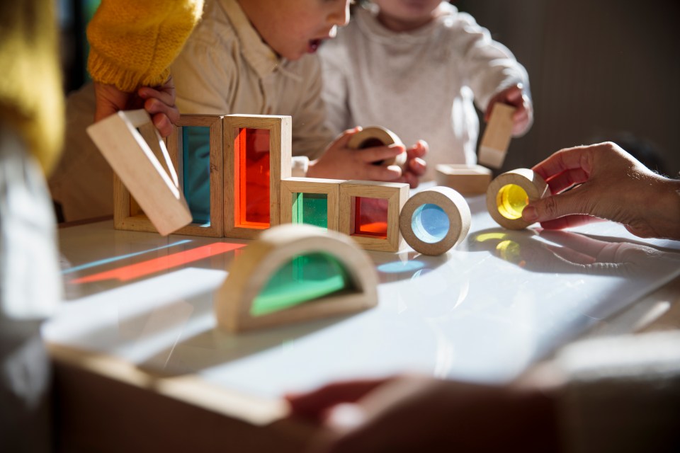 Young children playing with colorful translucent blocks.