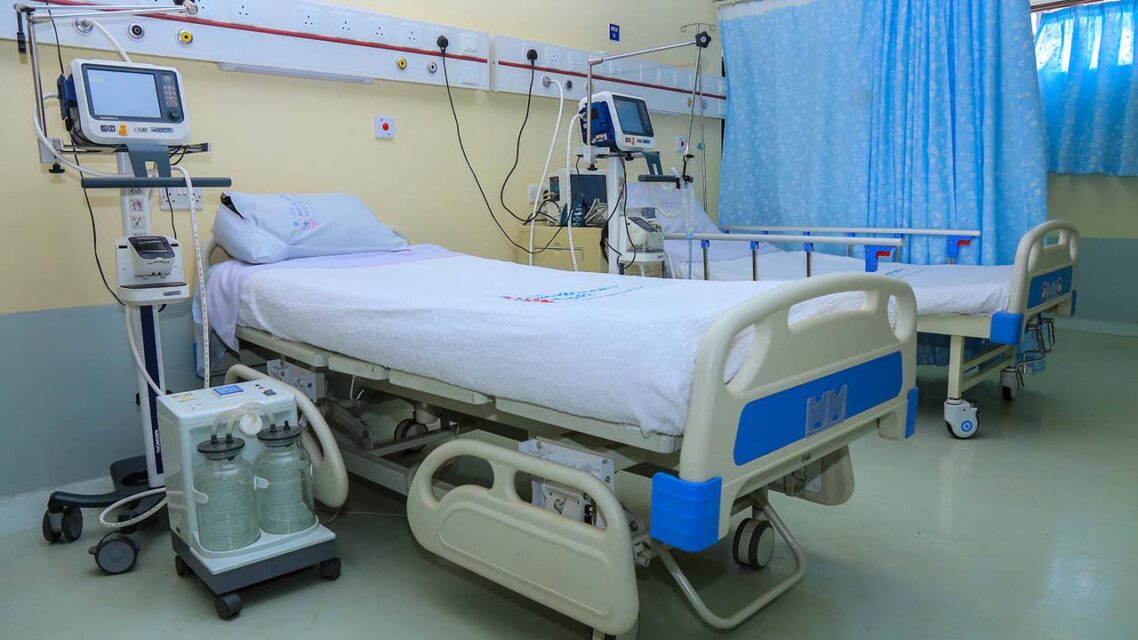 Photo of a hospital bed in a ward, with medical monitoring equipment beside the bed.