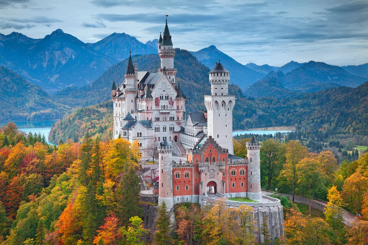view of Neuschwanstein Castle on october 7th near Hohenschwangau, Germany during autumn afternoon surrounded by fall colours.