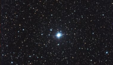 A nova shown as a bright blue star in the center of a field of stars.