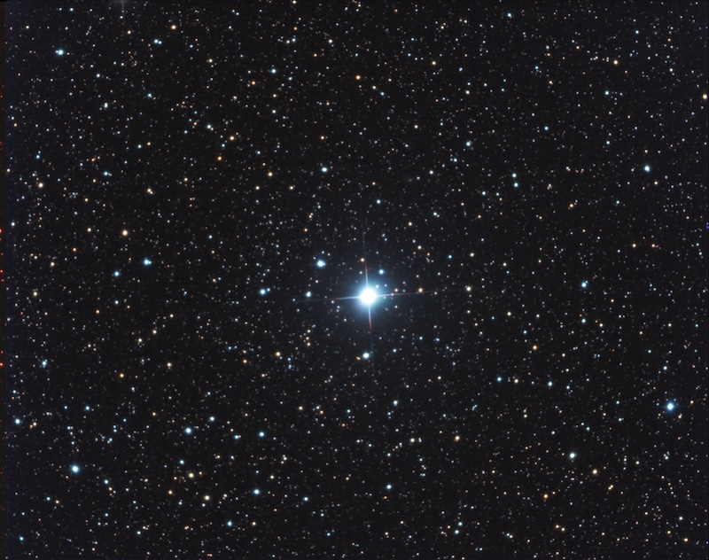 A nova shown as a bright blue star in the center of a field of stars.