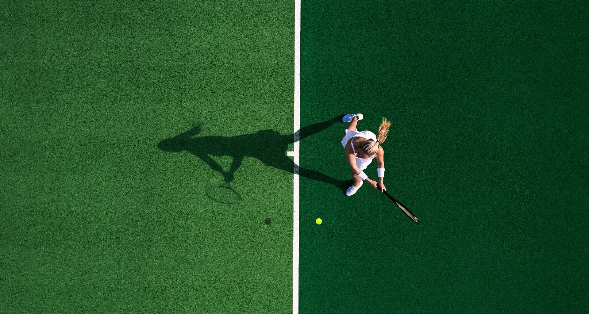 Bird's eye view of woman in whites playing tennis for longevity