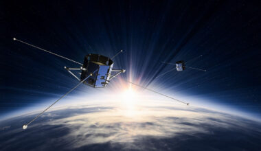 An illustration of two boxy satellites with long antennae floating above Earth in space