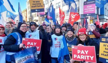 Striking nurses in Belfast holding RCN signs that say 'it's time to pay nursing staff fairly' and 'pay parity'
