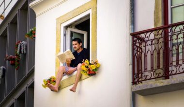 MP46X7 Man sitting on the window seal of an open window reading; man