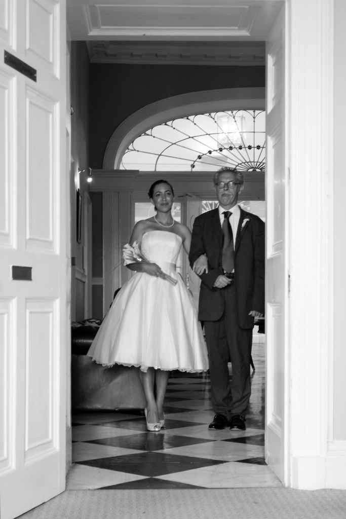 Image shows Emily in her wedding dress on her wedding day, arm-in-arm with her father Keith as they prepare to walk down the aisle.