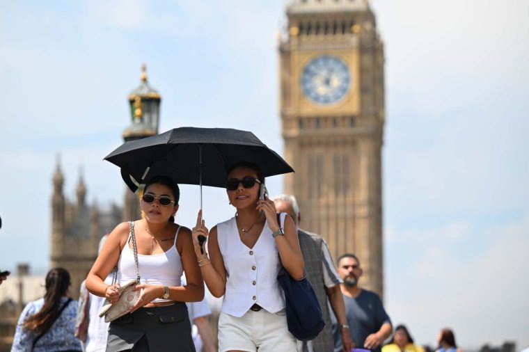 LONDON, UNITED KINGDOM - JULY 1: People are seen wearing caps and holding umbrellas at street near Big Ben in London, United Kingdom on July 1, 2025. The Met Office, weather forecasts for the UK, stated that temperatures could reach 35 degrees Celsius in different parts of the country. (Photo by Rasid Necati Aslim/Anadolu via Getty Images)