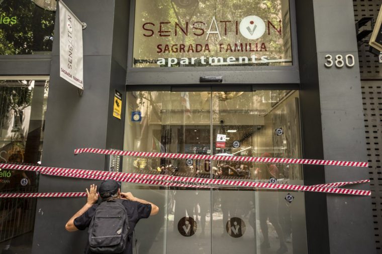A demonstrator applies a tape cordon to the entrance of tourist apartments during a protest called by the Neighborhoods Assembly for Tourist Degrowth (ABDT), in Barcelona, Spain, on Sunday, June 15, 2025. Many residents believe tourism has gone too far in the city famed for Antoni Gaudi's La Sagrada Familia basilica and the Las Ramblas promenade, running roughshod over communities and exacerbating a housing crisis. Photographer: Angel Garcia/Bloomberg via Getty Images