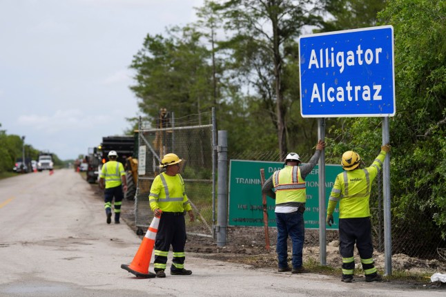 Workers install a sign reading 