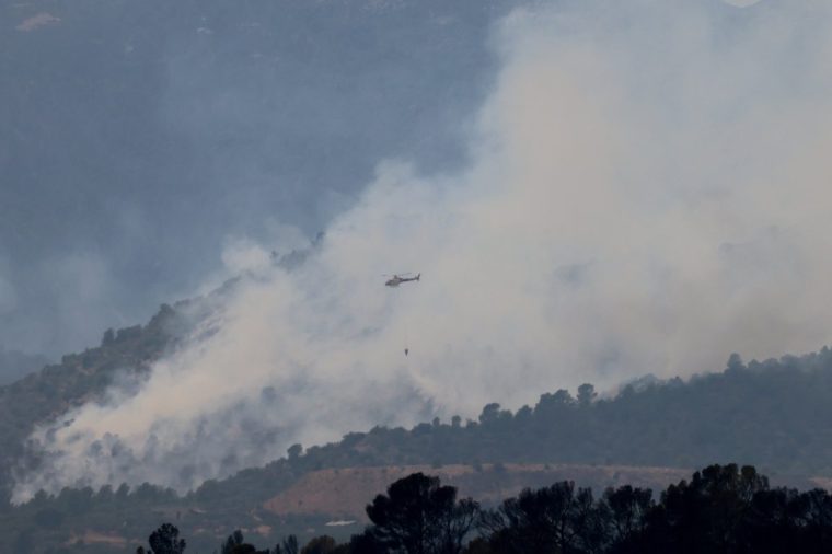 A helicopter flies as it helps to extinguish an ongoing wildfire in Xerta, which is one of the confined villages in the Tarrragona province in Catalonia, Spain, July 8, 2025. REUTERS/Nacho Doce