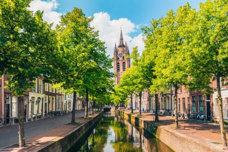 Canal with Leaning Church Tower in downtown district of Delft, South Holland, Netherlands.
