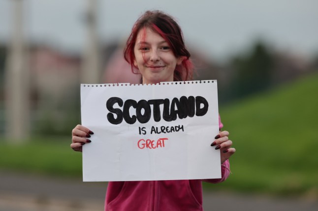 A young girl holds a sign for US President Donald Trump, as she awaits the president's arrival at his Turnberry golf course in South Ayrshire, as he begins his five-day private trip to the country. Picture date: Friday July 25, 2025. PA Photo. The US president is expected to head over to his Menie golf course in Aberdeenshire before opening up a new course dedicated to his Scottish mother, who grew up on the Isle of Lewis. Photo credit should read: Robert Perry/PA Wire